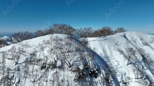 Aerial shot push in over top of Myoko Mountain Summit, on clear winter day coast line and ocean sea in background. Japan mount myōkō a volcanic mountain in Myoko-Togakushi Renzan National Park region photo