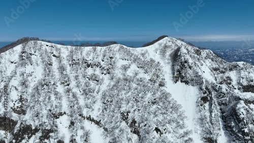 Aerial fly over shot of top of Myoko Mountain Summit, Japans coast line and ocean sea visible in background. Japan mount myōkō a volcanic mountain in Myoko-Togakushi Renzan National Park region photo