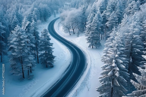 Aerial view of windy road in snow covered forest.