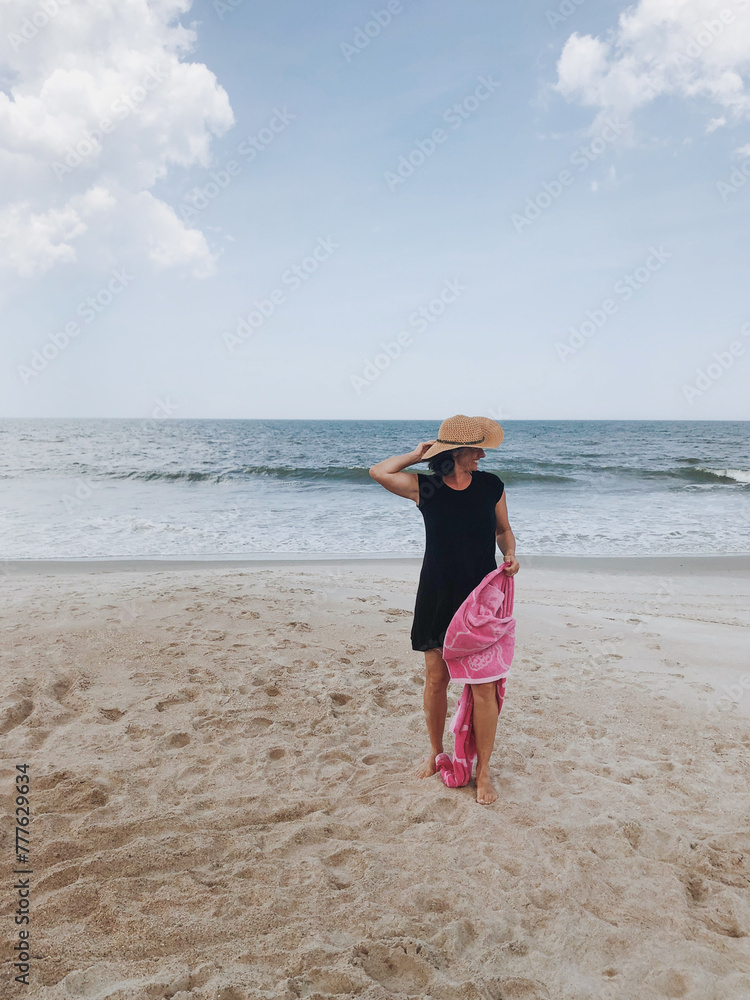 Fashionable woman with hat walking on the beach