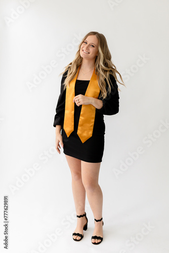 Graduation photo in a studio, girl smiling with black and gold s