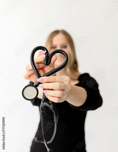 Woman nurse smiling holding a stethoscope in a heart shape, bran