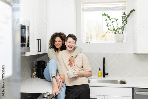 Couple shares a laugh over coffee in a sunlit, stylish kitchen