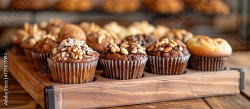 A wooden tray holds freshly baked muffins topped with assorted nuts. The muffins are placed neatly on the tray, showcasing their delicious and nutty toppings. photo