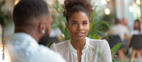 A woman, possibly a HR professional, engages in conversation with a man at a table in a restaurant setting. photo