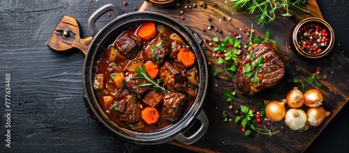 A pot filled with German style braised beef cheeks in a rich red wine sauce, cooked with tender carrots and onions. photo
