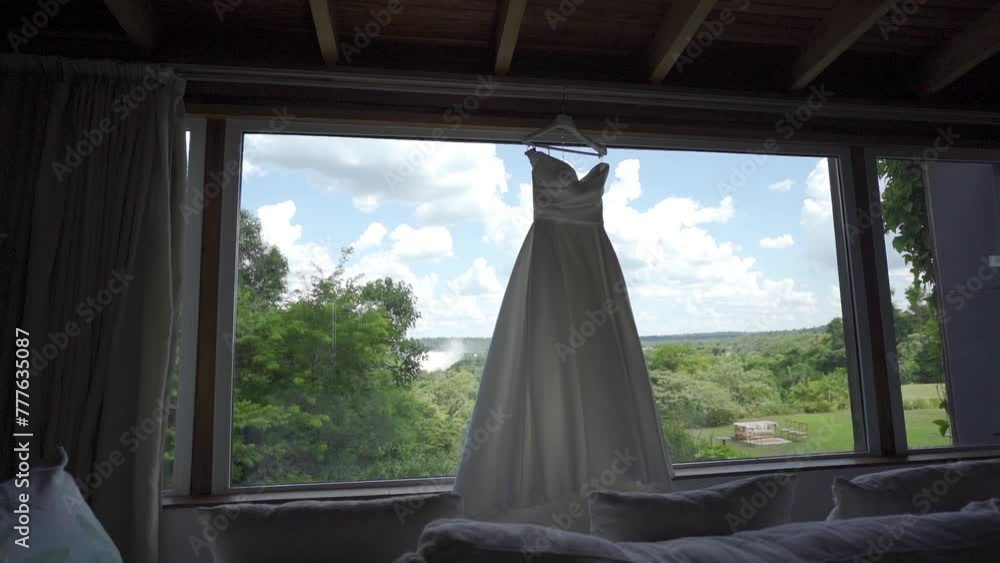Bride's dress hanging on the open window of the room with a view of the landscape of the Iguazu Falls Bride's dress hanging on the open window of the room with a view of the landscape of the Iguazu Falls