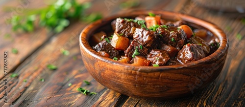 A wooden bowl filled with hearty Belgian beef stew, chunks of tender meat, potatoes, carrots, and onions. photo