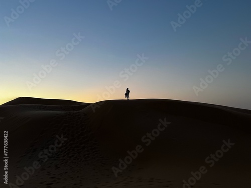man on dunes silhouetted against sky at sunset, outdoors