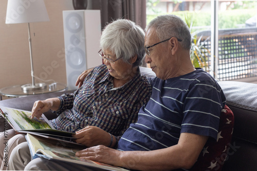 senior couple watching photo album  together on couch at home photo