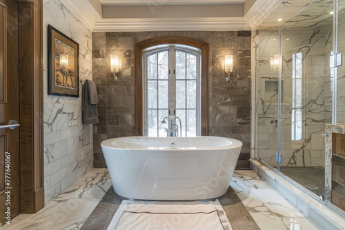 A large white bathtub sits in a bathroom with a marble wall and a glass shower