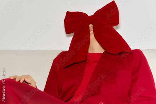 Female with a big red bow hiding her face photo