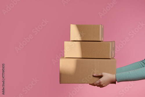 Delivery handing parcel box to recipient on pink background photo