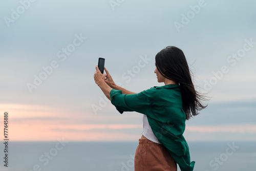 Smiling woman taking selfies during peaceful sea sunset