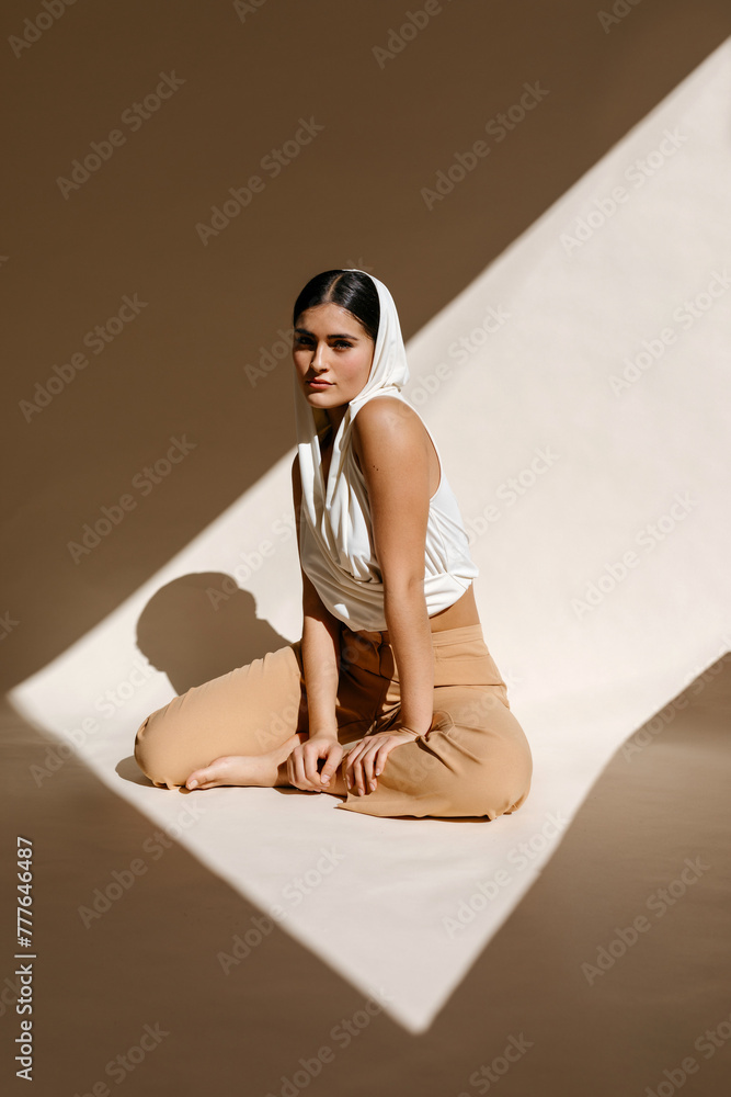 Calm woman with folded legs sitting on floor and looking at camera Calm woman with folded legs sitting on floor and looking at camera