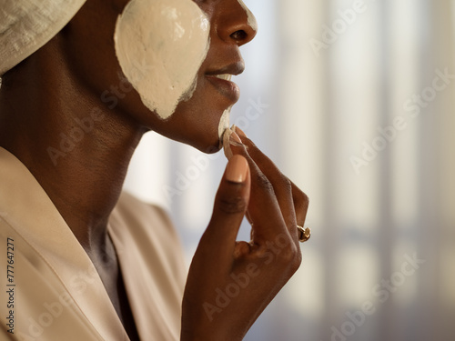 Woman applying purifying mask on face photo