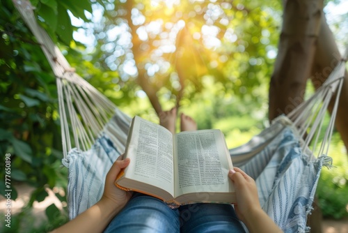 Relaxing in a hammock with a book in a green, sunlit garden photo