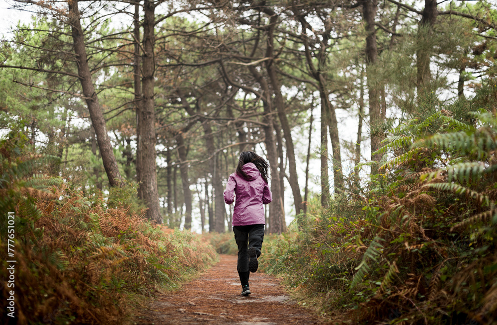 Woman jogging across foggy forest Woman jogging across foggy forest