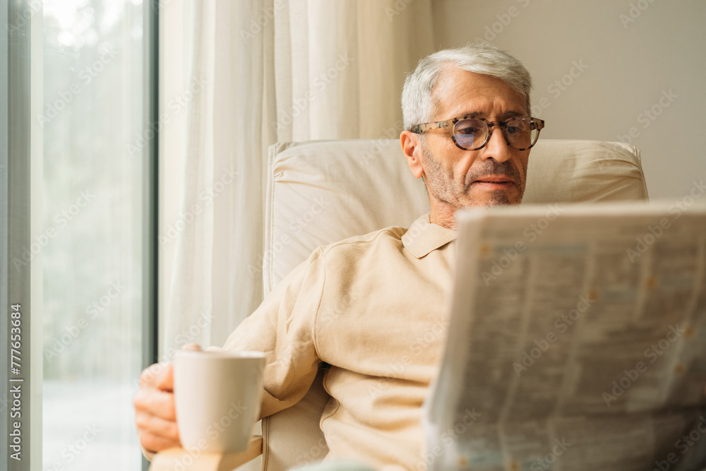 Senior man reading newspapers in his home Senior man reading newspapers in his home