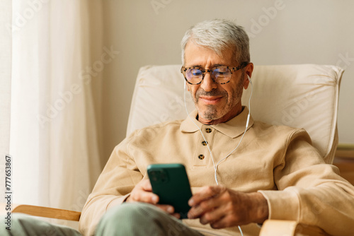 Senior man using his cell phone with earbuds photo