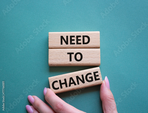 Need to change symbol. Concept words 'Need to change' on wooden blocks. Beautiful grey green background. Businessman hand. Business and Need to change concept. Copy space.