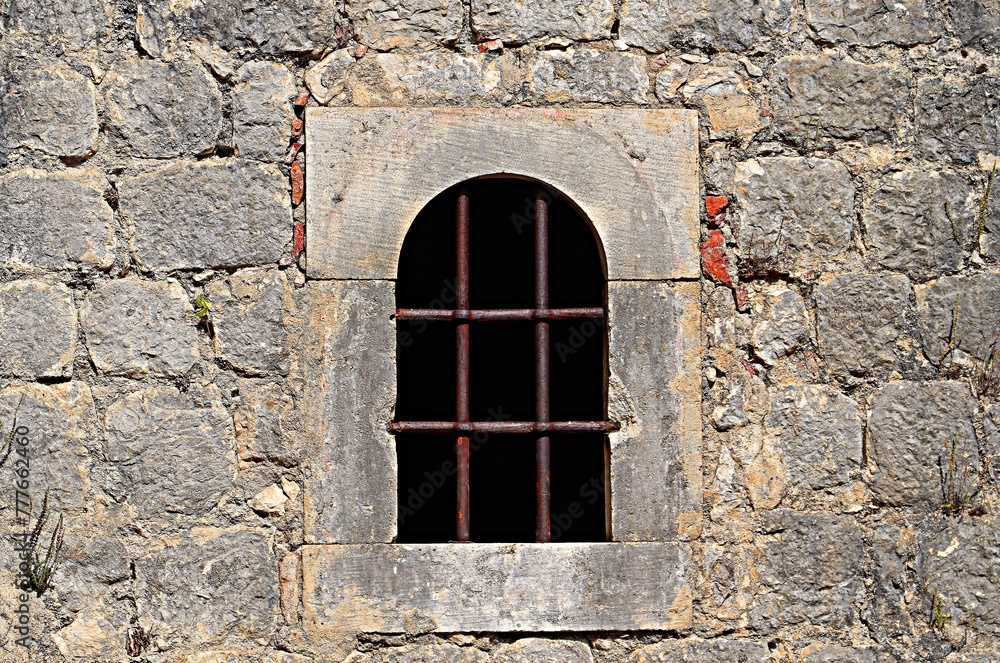 Window in an old fortress covered with iron bars