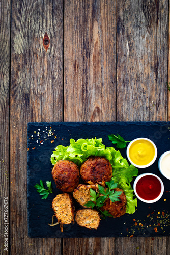 Fried meatballs on black stony plate on wooden table
