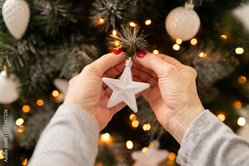 Person decorating Christmas tree with white ornaments photo