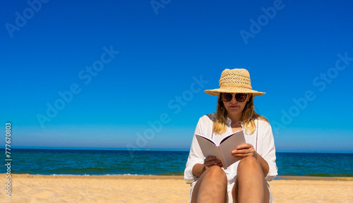 Woman sitting on beach reading book 