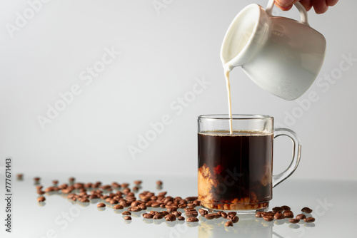 Pouring milk in black coffee.