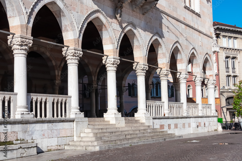 Exterior view of columns of Loggia del Lionello on main square Piazza della Liberta in historic old town Udine, Friuli Venezia Giulia, Italy, Europe. Italian classic architecture with arches, columns