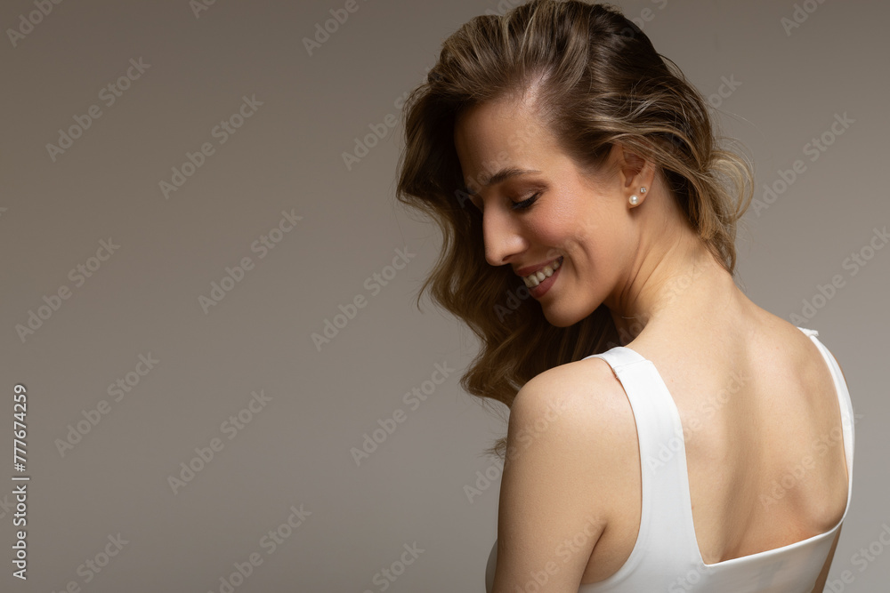 young blonde woman with curly beautiful hair smiles on a gray background young blonde woman with curly beautiful hair smiles on a gray background