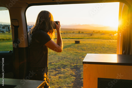 Photographer by her camper van taking a photo at sunset  photo