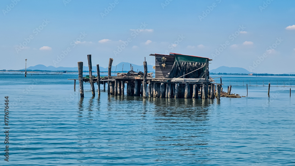 Scenic view of wooden fishing huts on stilts of fishermen of Pellestrina in the Venetian lagoon, Pellestrina, Veneto, Italy, Europe. Adriatic Mediterranean sea in summer with blue sky. Tourism Venice