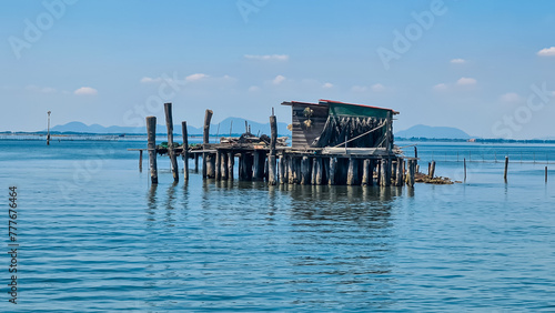 Scenic view of wooden fishing huts on stilts of fishermen of Pellestrina in the Venetian lagoon, Pellestrina, Veneto, Italy, Europe. Adriatic Mediterranean sea in summer with blue sky. Tourism Venice