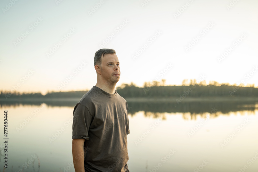 portrait of young man with down syndrome next to a river at sunset
