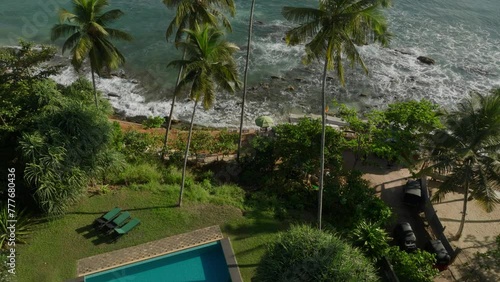 Droneshot of people walking on the shore at Hiriketiya Beach, Sri Lanka with crushing waves on the shore