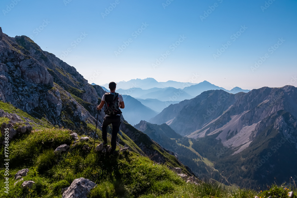 Hiker man with scenic view of mountain peak Grintovec, majestic Kamnik-Savinja Alps, Slovenia, Europe. Magnificent hiking trail in untamed Karawanks, Austrian border. Magical mountains Slovenian Alps