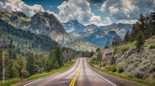 Asphalt road stretching into mountainous wilderness under a cloudy sky © AIS Studio