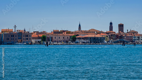 Panoramic view of historic landmarks of charming town of Chioggia seen from Sottomarina, Venetian Lagoon, Italy. Seagull sitting on wooden pole. Known as little Venice. Urban vacation in summer