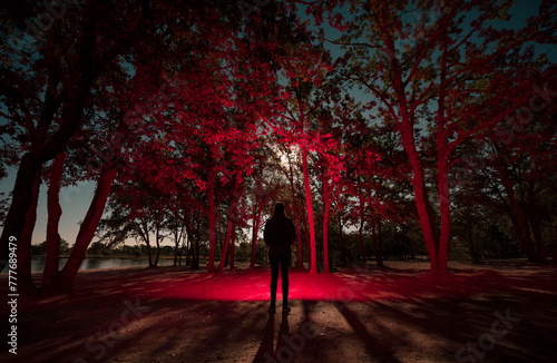 Dreamlike human in forest with red light at night photo