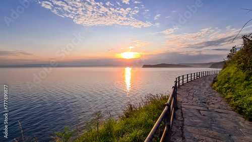 Scenic walking path at sunrise between Fiesa and charming coastal town of Piran in Slovenian Istria, Slovenia, Europe. Rugged rocky cliffs gracefully perched above shimmering waters of Adriatic Sea