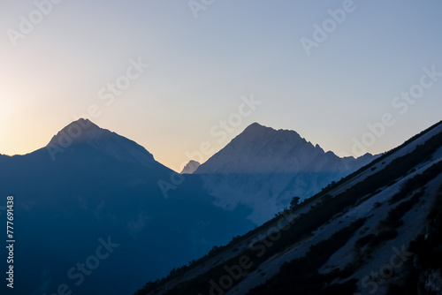 Panorama of stunning sunrise with golden sun beams over majestic summits of untamed Karawanks mountain range. Vantage point of Loibl Pass, border Austria Slovenia. First rays of morning sun in Alps photo