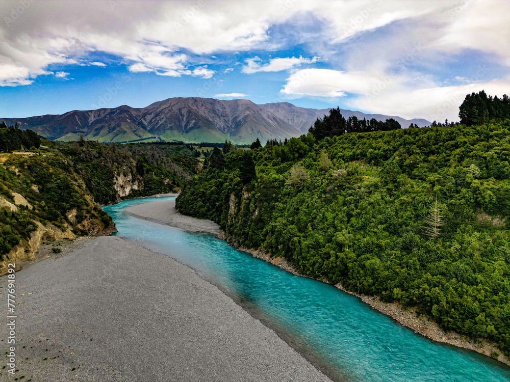 Bright turquoise blue glacier water runs down pebble banked stream towards mountains. Rakaia Gorge, New Zealand. Bright turquoise blue glacier water runs down pebble banked stream towards mountains. Rakaia Gorge, New Zealand.