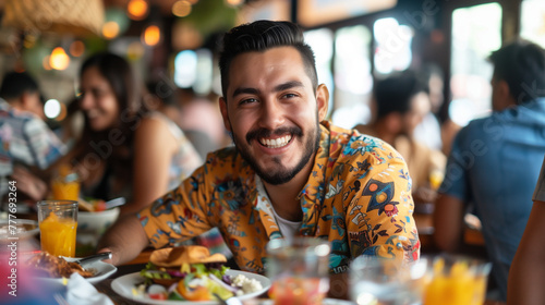Young cheerful man having lunch with friends in Mexican restaurant