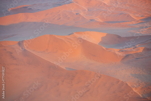 Fototapeta Naklejka Na Ścianę i Meble -  Breathtaking sunrise over the sand dunes of Sossusvlei, Namibia, captured from a helicopter. The first light of dawn casts dramatic shadows and highlights the vibrant colors of the desert.