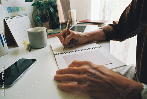 Senior person writing by the desk photo