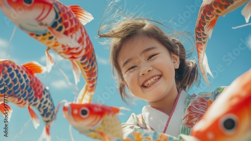 Happy little Japanese girl with koi fish on blue sky background. Concept of Celebrate Golden Week in Japan or National Koi Day. Children’s Day in Japan. Kodomo no Hi photo