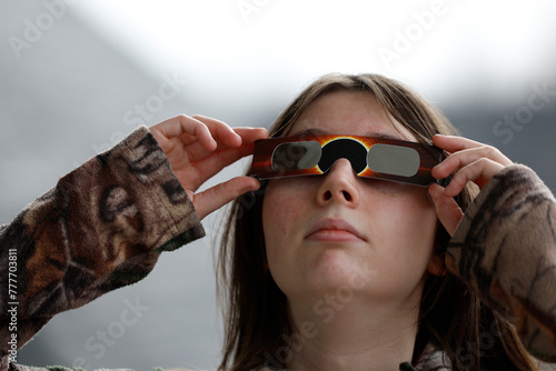 Une jeune adolescent regarde l'éclipse solaire avec des lunettes de protection