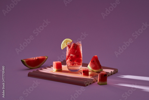 A glass of watermelon juice with pieces of lemon and ice on ligh photo